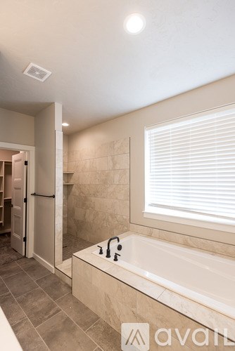 A bathroom with a tub and a window with blinds.