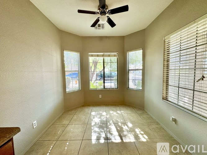 A room with a ceiling fan and three windows.