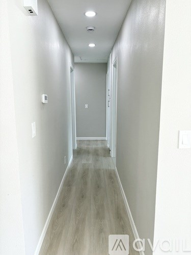 A long hallway with wood flooring and white walls.