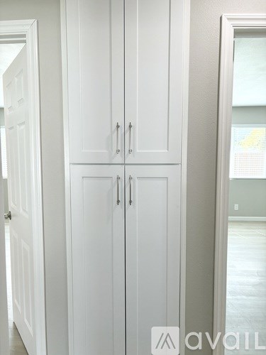 A white double door cabinet with two handles.