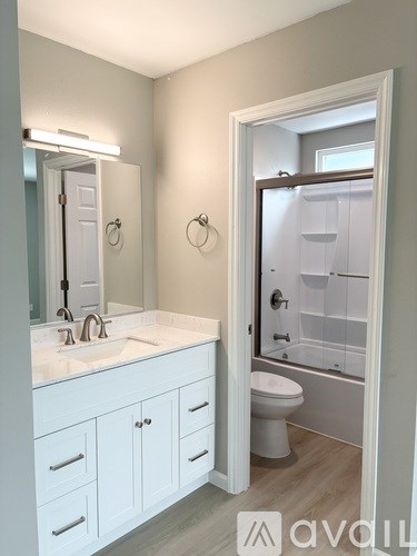 A bathroom with a white sink and cabinets.