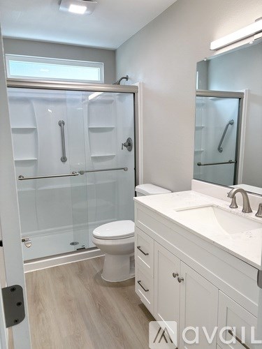 A white bathroom with a toilet, sink, and shower.
