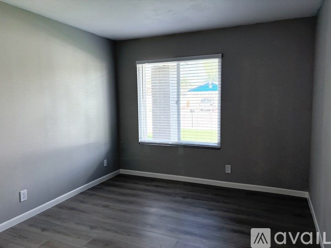 A room with a window and a wooden floor.