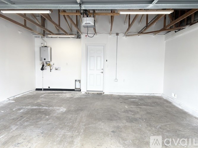 A room with a door, a wall-mounted heater, and exposed ceiling beams.