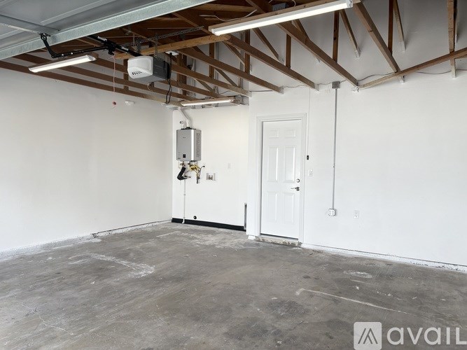 A room with a white door and a white wall with wooden beams on the ceiling.