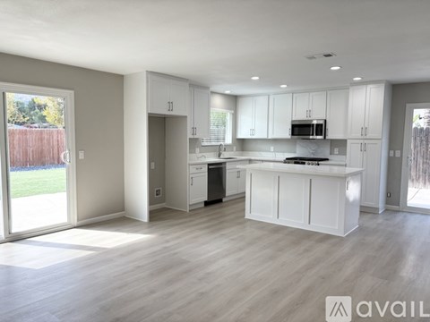 A spacious kitchen with white cabinets and a wooden floor.