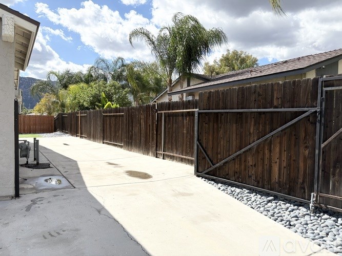 A long driveway with a wooden fence and gate.