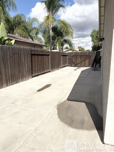 A backyard with a wooden fence and a concrete patio.