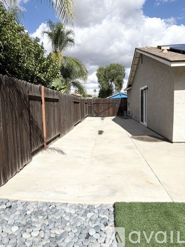 A backyard with a wooden fence and a house in the background.
