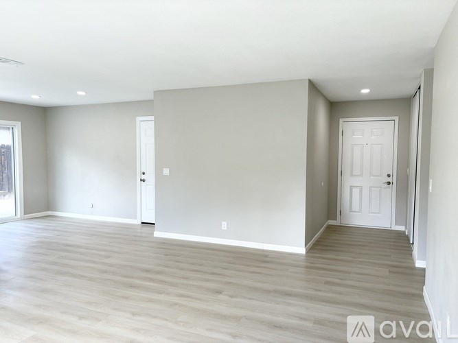A spacious room with light grey walls and wooden flooring.