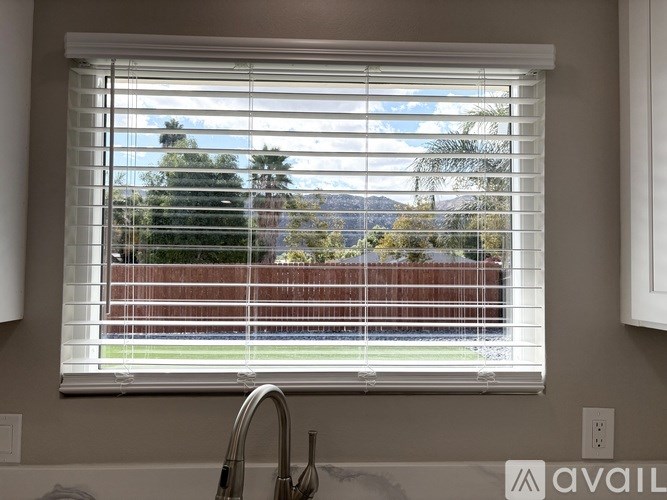 A kitchen with a window covered in white blinds.