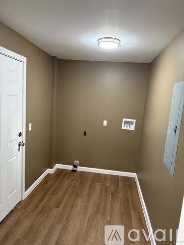 A room with a white door and a brown floor.