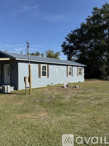 A blue house with a metal roof and a sign in front of it.