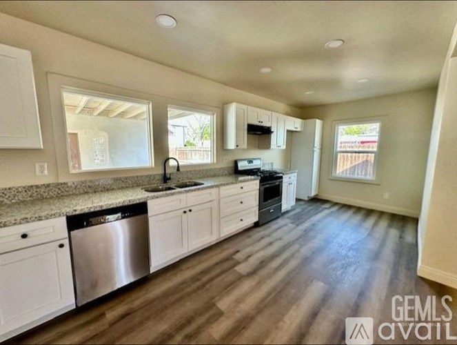 A kitchen with white cabinets and a wooden floor.