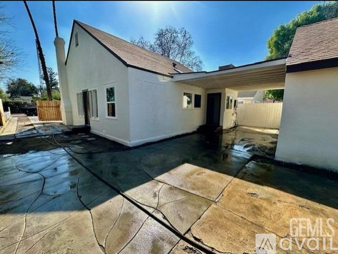 A white house with a brown roof and a driveway in front.
