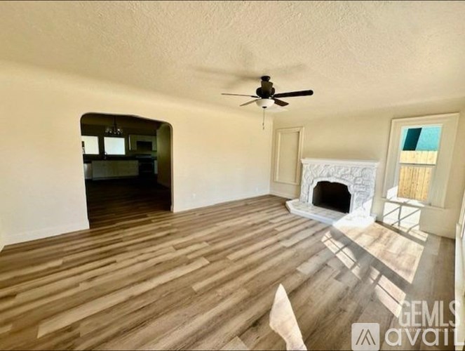 A living room with a fireplace and a ceiling fan.