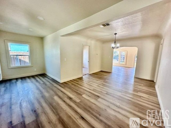 A spacious room with wooden floors and a chandelier.