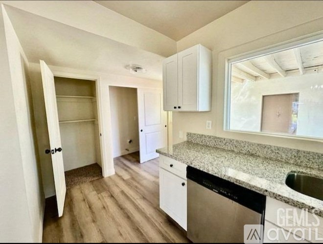 A kitchen with a granite countertop and white cabinets.