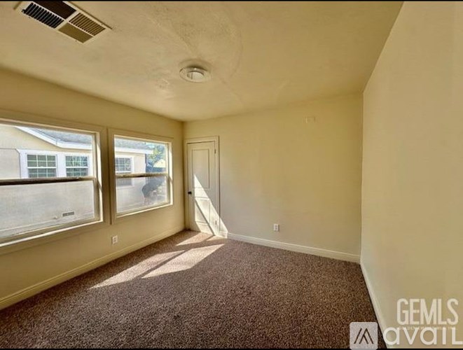 A room with a carpeted floor and a door leading to another room.