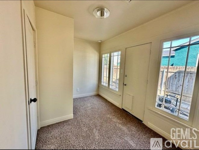 A room with a carpeted floor and a window showing an outdoor view.