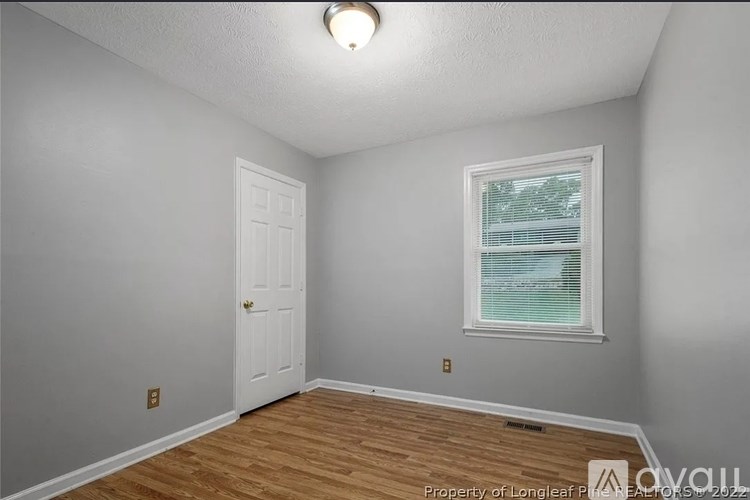 A room with a white door and a window with blinds.