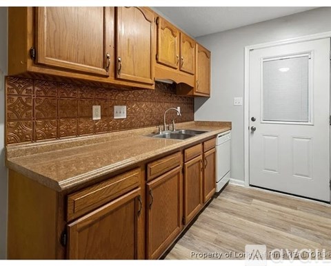 A kitchen with wooden cabinets and a white door.
