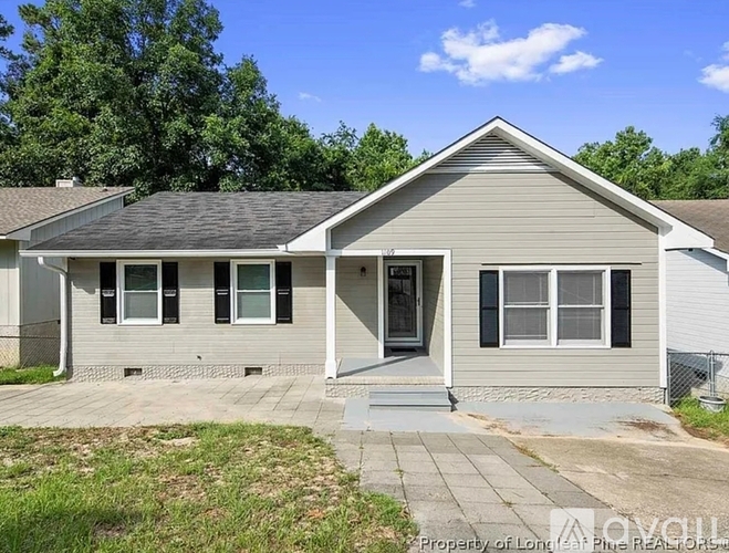 A house with a grey roof and a white fence is for sale.