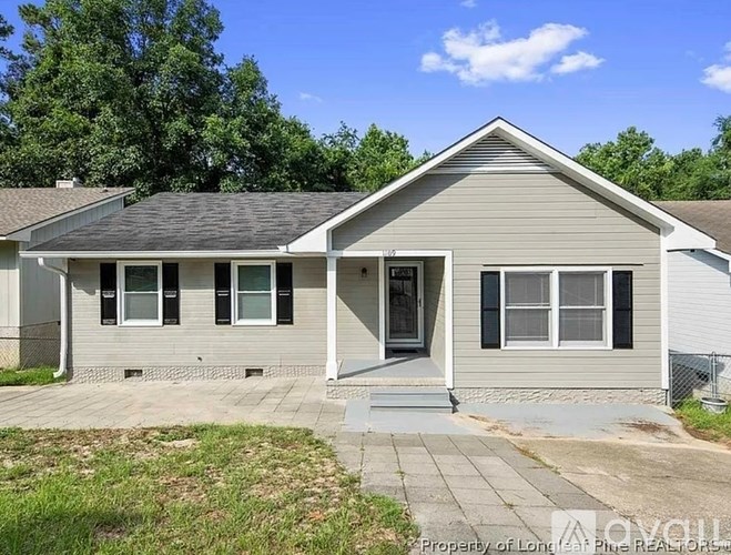A house with a grey roof and a white fence is for sale.