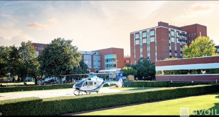 A helicopter is parked on a green lawn in front of a red brick building.