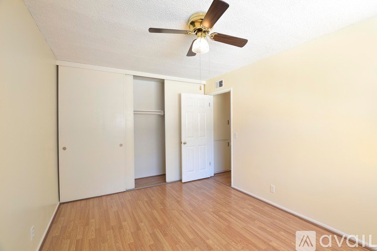 A room with a ceiling fan and wooden flooring.