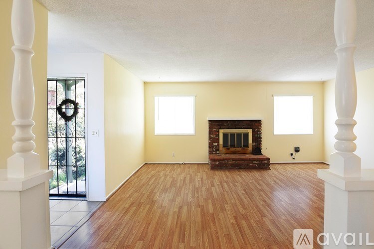 A large empty room with a fireplace and wooden floors.