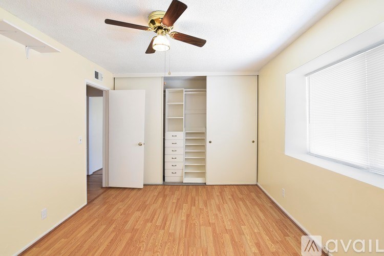 A room with a ceiling fan and wooden floors.