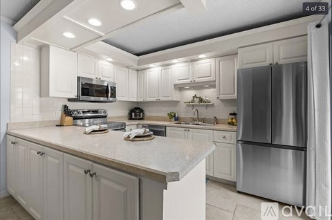 A kitchen with white cabinets and a stainless steel refrigerator.