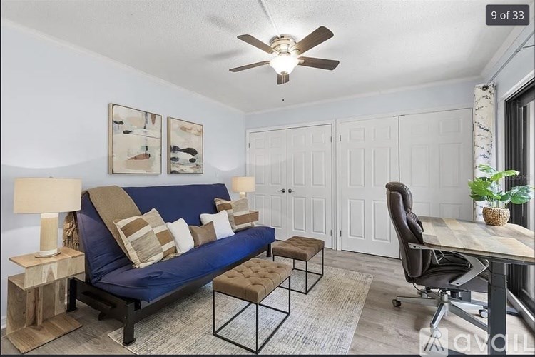 A living room with a blue couch, a wooden coffee table, and a ceiling fan.