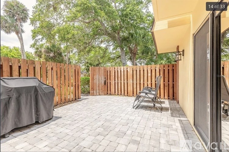 A patio with a table and chairs is surrounded by a wooden fence.