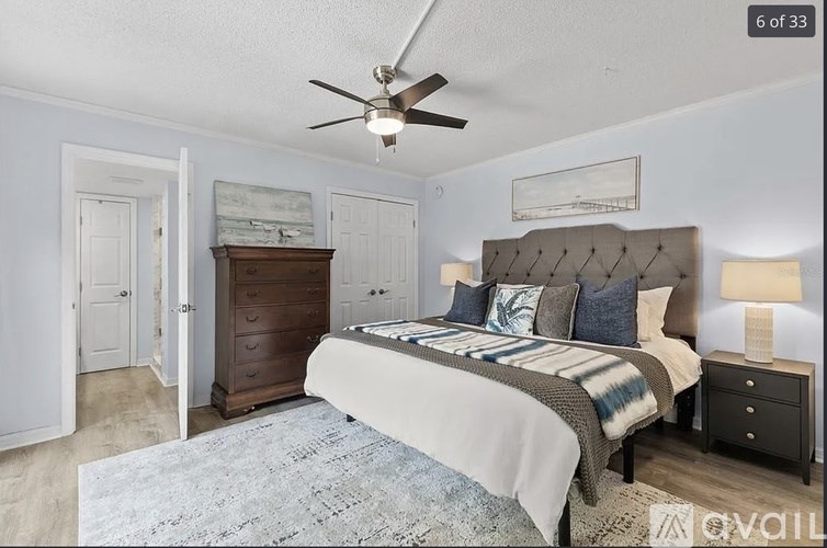 A bedroom with a bed, dresser, and ceiling fan.