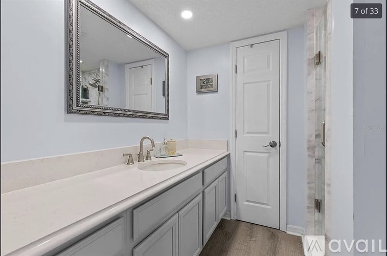 A bathroom with a sink, mirror, and a white door.
