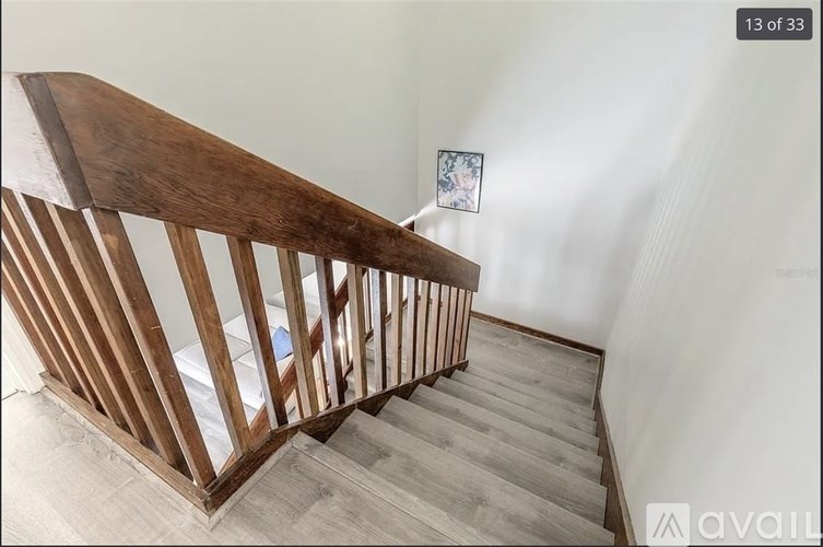 A wooden staircase with a white wall and a picture on the wall.