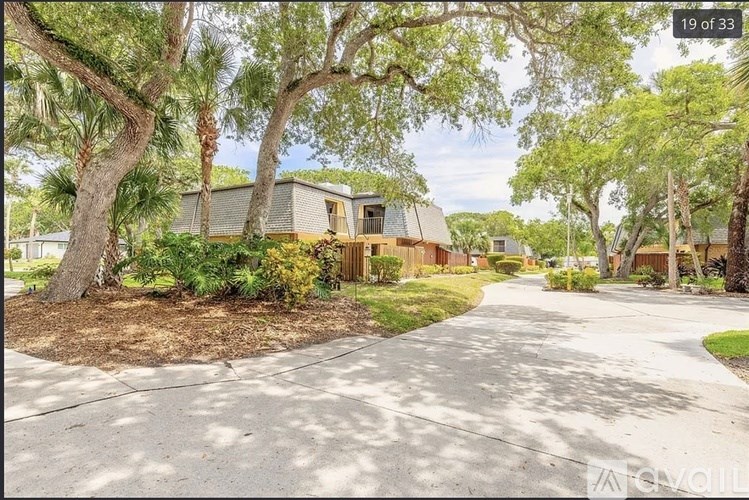 A house is surrounded by trees and has a driveway in front.