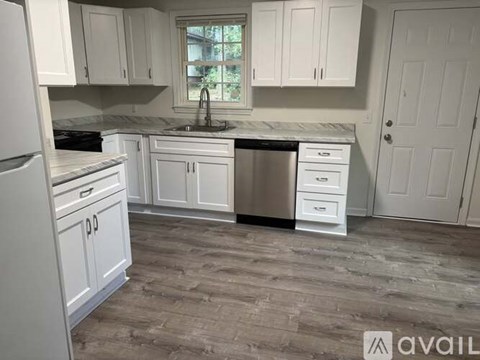 A kitchen with white cabinets and a marble countertop.