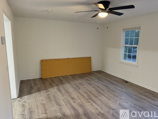 A room with a ceiling fan and a window with a white frame.