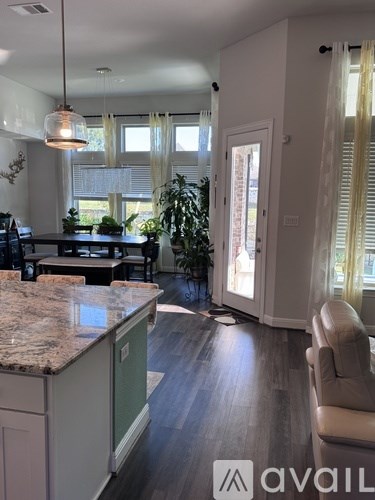 A kitchen with granite countertops and a dining area with a table and chairs.