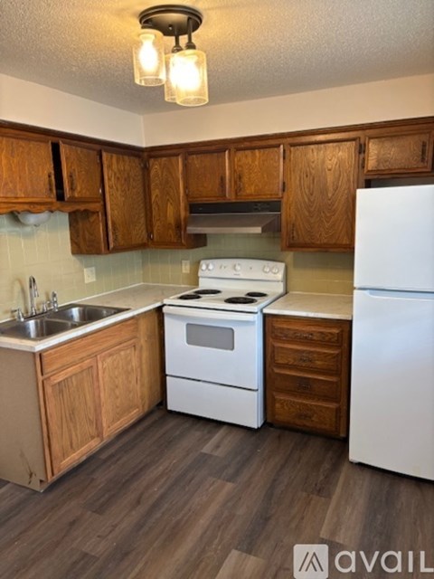 A kitchen with wooden cabinets and a white stove top oven.
