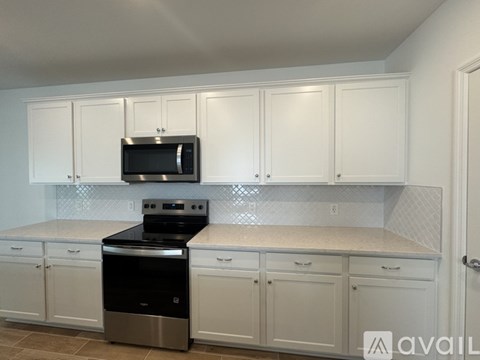 A kitchen with white cabinets and a black dishwasher.