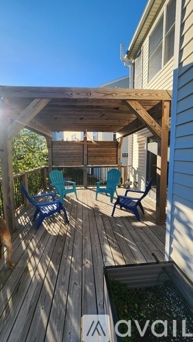 A wooden deck with a pergola and blue chairs.