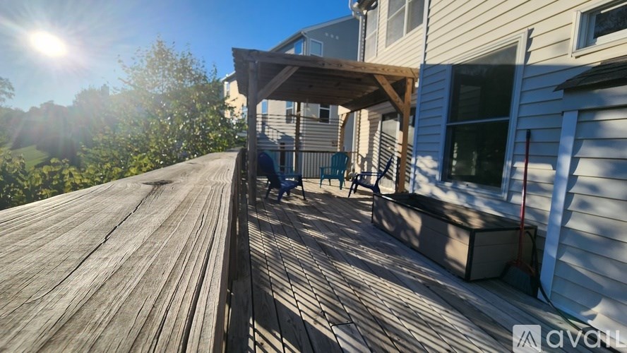 A wooden deck with a person sitting on a chair under a pergola.