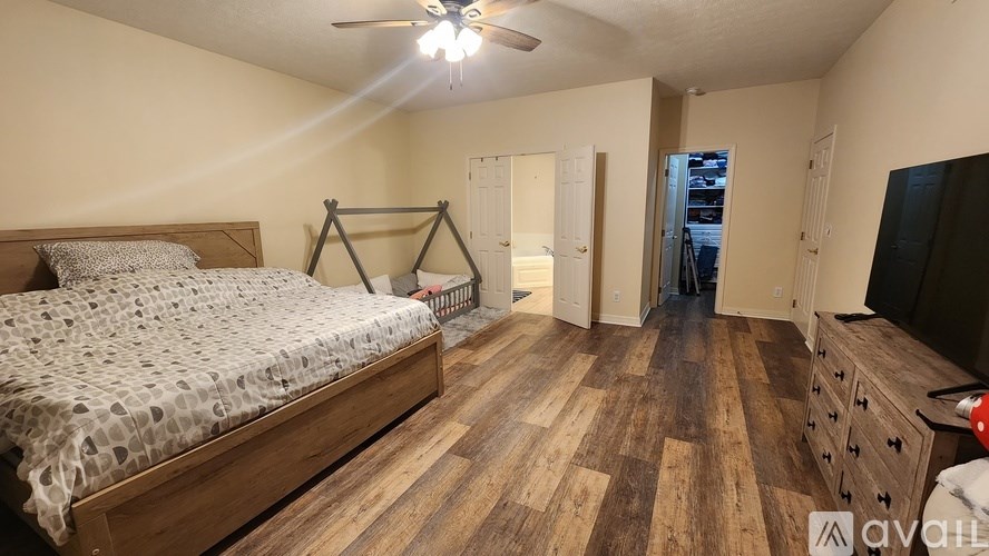 A bedroom with a bed, dresser, and a ceiling fan.
