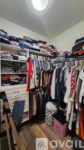 A room full of clothes on shelves and hanging on a rack.