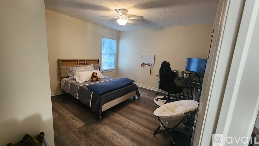 A woman is sitting on a chair in a room with a bed and a baby bassinet.