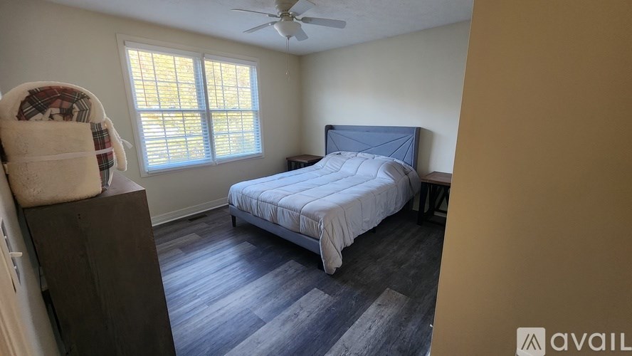 A bedroom with a bed, dresser, and window.